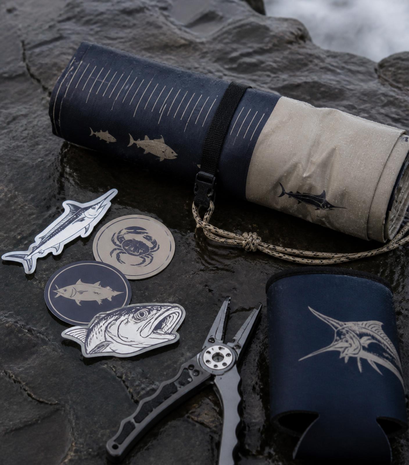 SaltVector brag mat and vinyl stickers laid out on wet coastal rock
